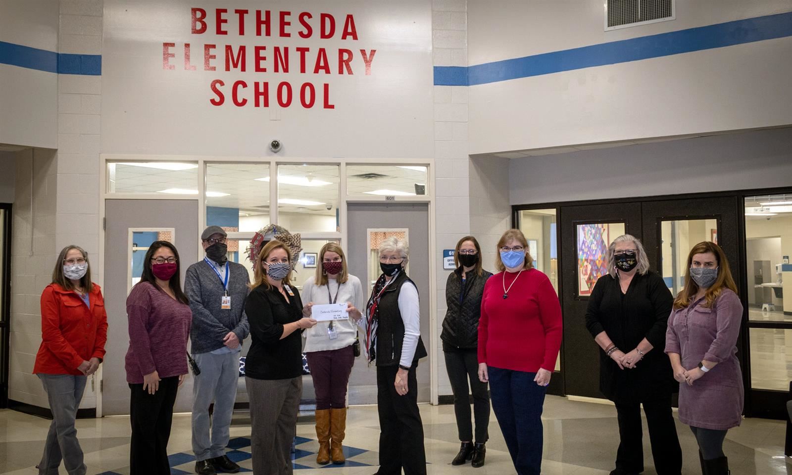 Teachers stand and hold a paper check 